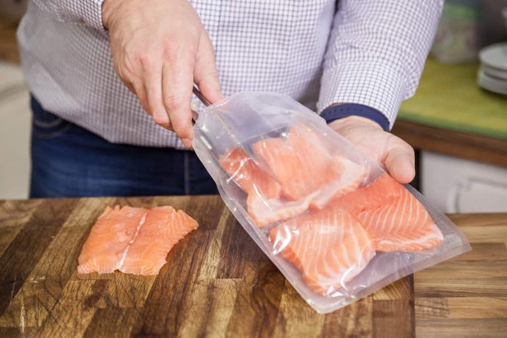 person putting pieces of salmon in sous vide bag