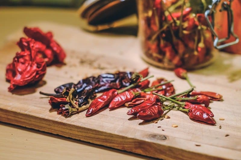 hot peppers on cutting board with mason jar in background