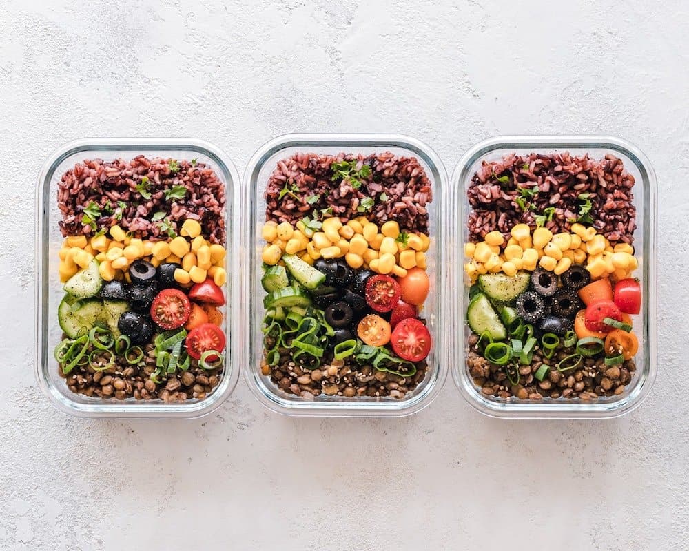 three meal prep containers in a row filled with food