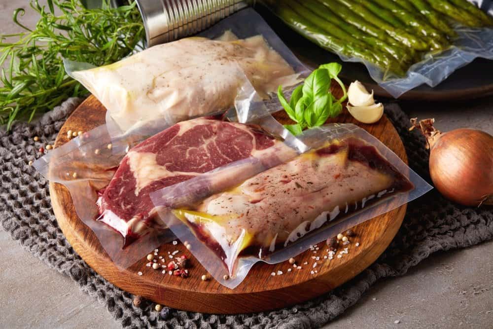 meat vacuum packed in sous vide bags with seasoning on chopping board