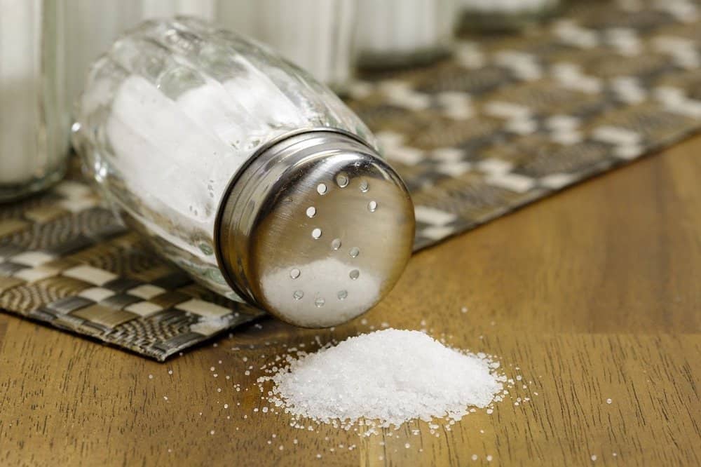 knocked over table salt shaker with salt spilled on table