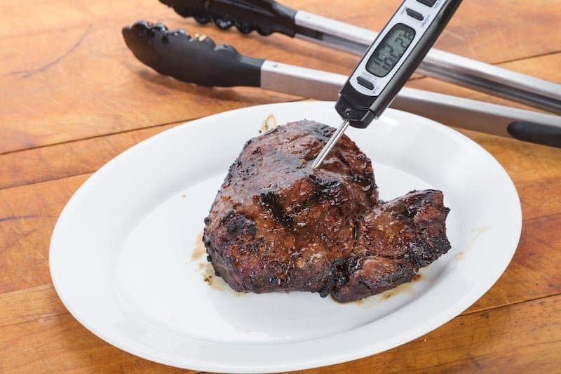 piece of cooked meat on plate with food thermometer