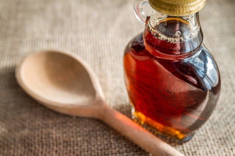 wooden spoon glass bottle of maple syrup