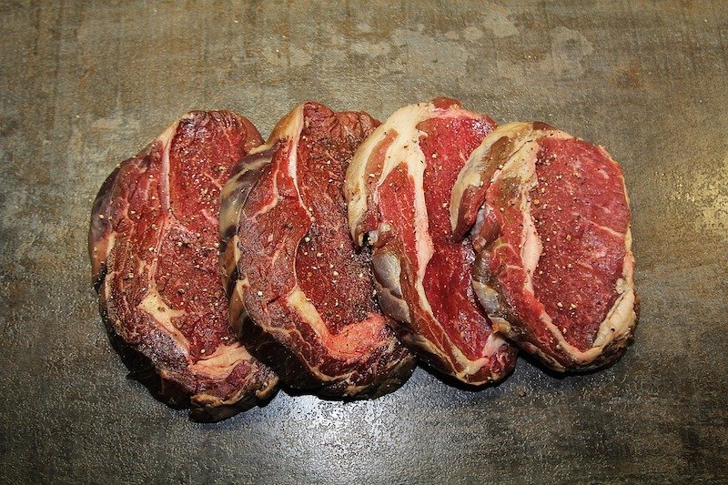 four seasoned steaks lined up in a row