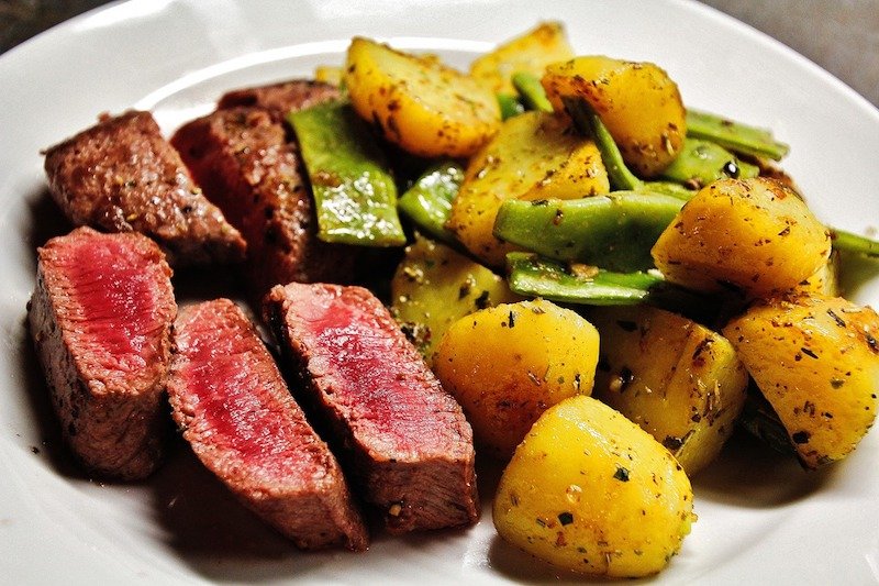 plate of steak cut into slices and potatoes