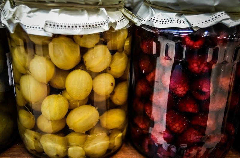 jar of fruit and jar of raspberries fermenting