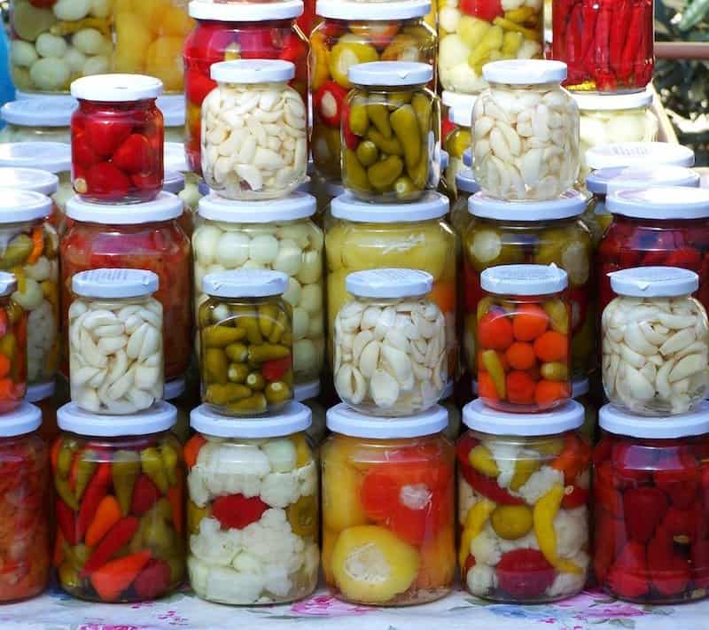 many stacked jars of various pickled vegetables