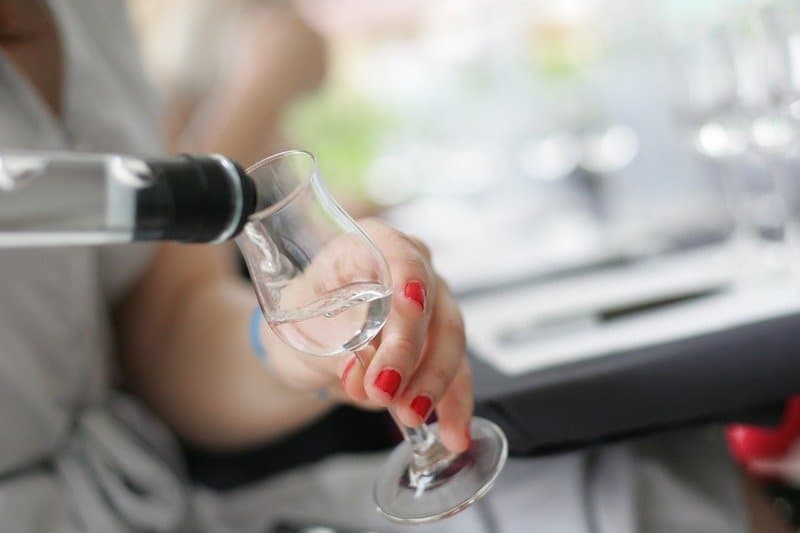 woman pouring clear brandy into glass