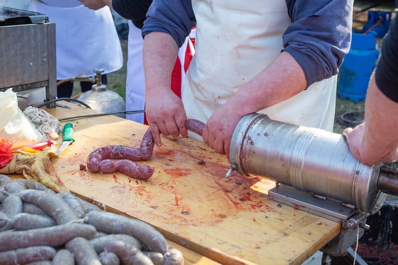 two men operating horizontal sausage stuffer to stuff sausage into casings