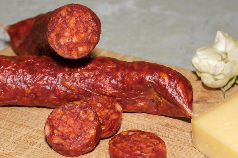 chorizo on cutting board with slices next to it and cheese