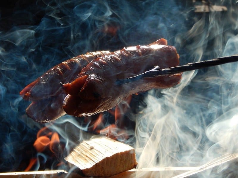 sausage on stick being smoked over fire