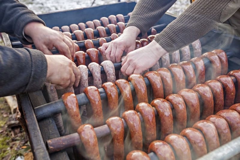 pessoas pendurando salsicha de veado em fumante