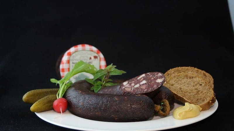 salchicha de ciervo en plato con pan de mostaza y encurtidos