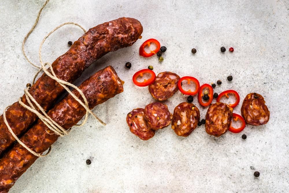 spanish chorizo tied with string with slices of chorizo and red chili pepper