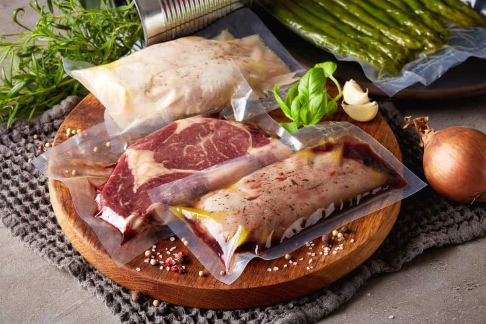 vacuum sealed chicken steak and pork on chopping board with seasonings