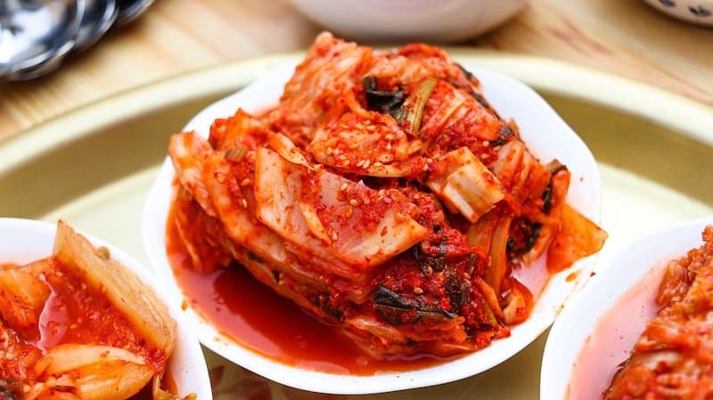 three white plates with piles of kimchi