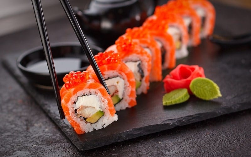 row of uramaki rolls with salmon and roe on top