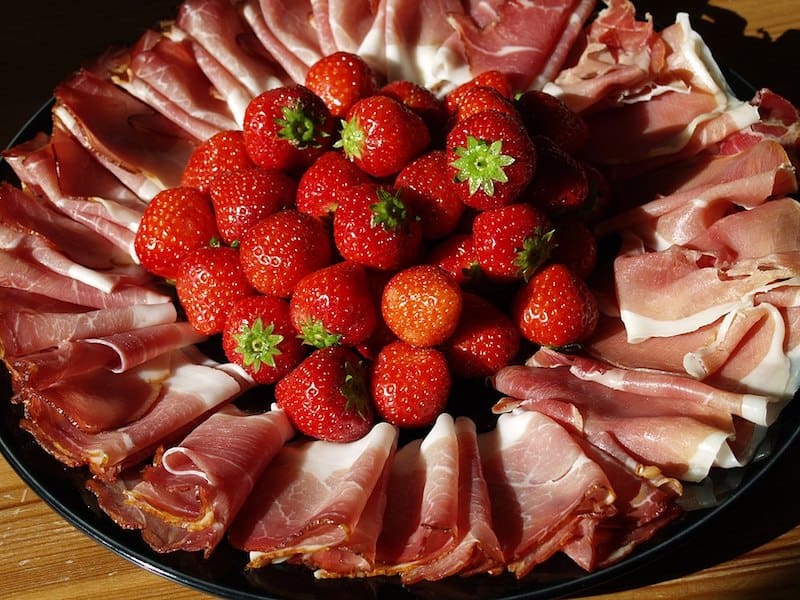 prosciutto on round platter with whole strawberries in the middle