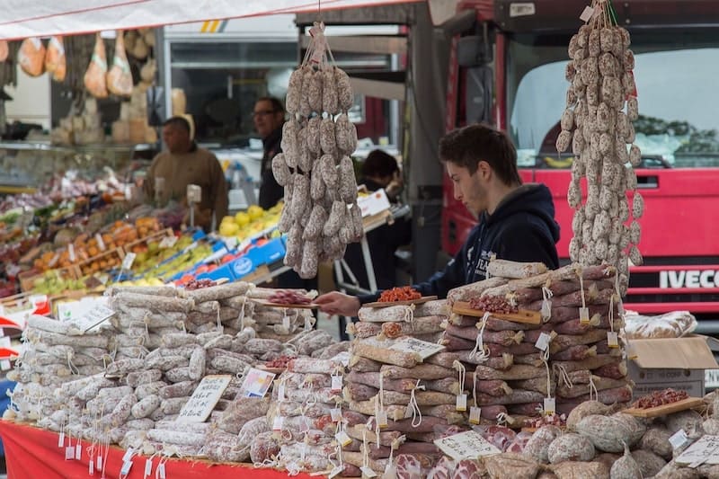 man in market selling sausage with white mold on outside